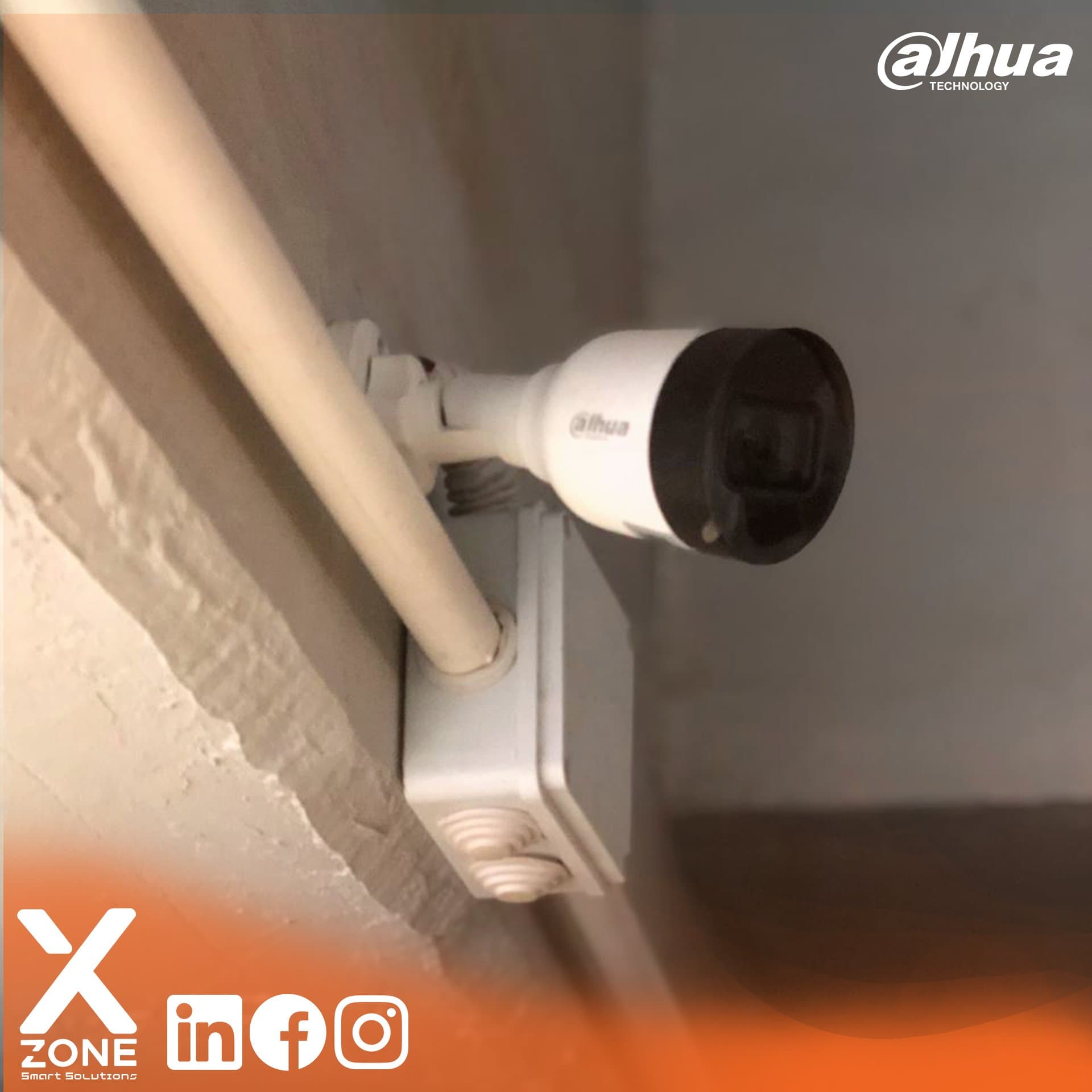 White Dahua bullet security camera mounted on a wall with a junction box and conduit.