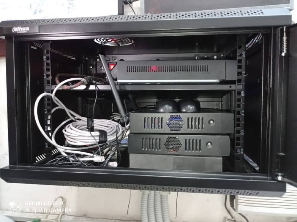 Black Dahua network cabinet containing stacked security devices and a bundle of white Ethernet cables.