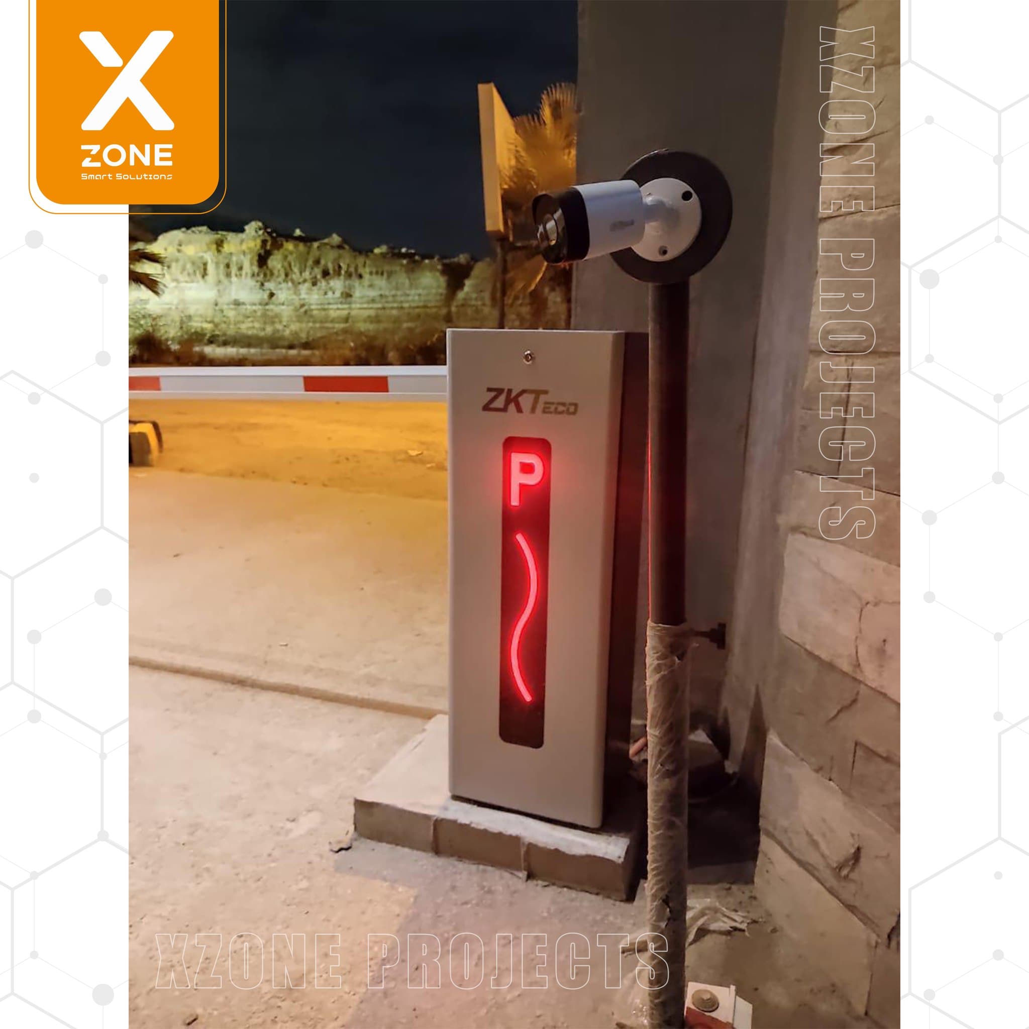 ZKTeco parking barrier system with a glowing red 'P' indicator and security camera at night.